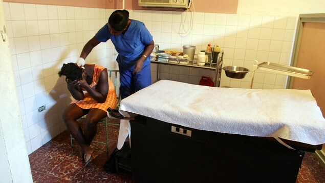 Une femme se tient la tête dans les mains tandis qu'une infirmière soigne sa blessure. Une femme se tient la tête dans les mains tandis qu'une infirmière soigne sa blessure.