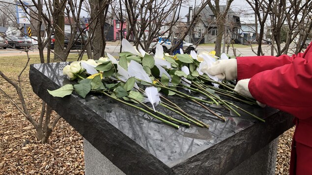 Une personne dépose des gerbes de fleurs.