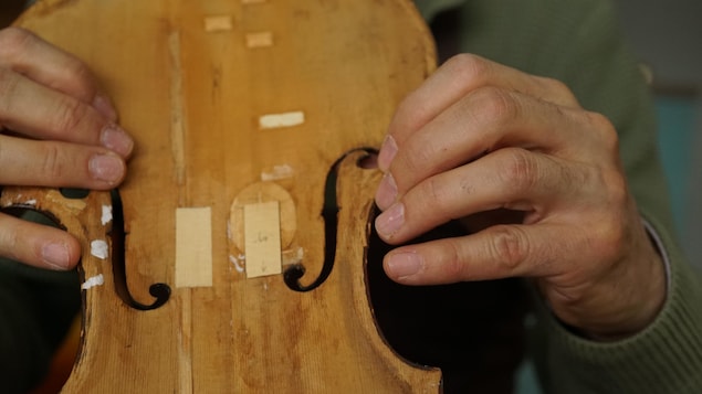 Les doigts du luthier ajustent la pièce dans la table d'harmonie d'un violon.