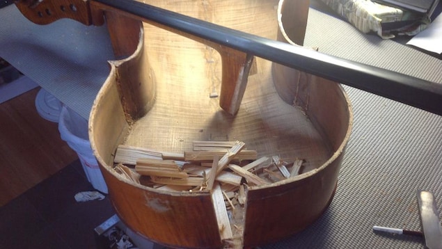 Un violoncelle en morceaux contenant de nombreuses éclisses de bois et posé sur une table. Un violoncelle en morceaux contenant de nombreuses éclisses de bois et posé sur une table.