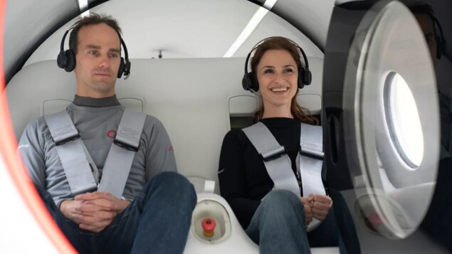 Deux personnes attachées à bord d'une cabine ronde de couleur blanche.