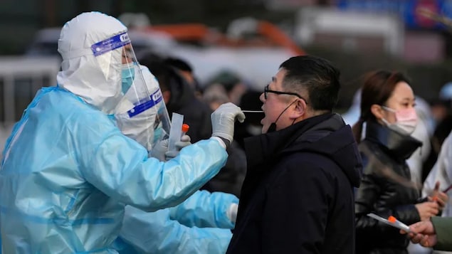 A man gets a throat swab for the COVID-19 test at a mobile coronavirus testing facility outside a commercial office building in Beijing on Jan. 17, 2022. Beijing's first reported case of the Omicron variant has prompted stepped-up measures in the nation's capital, just weeks before it hosts the Winter Olympic Games.