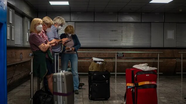 Passengers check their phones at Johannesburg's OR Tambo's airport on Nov. 29, 2021, days after Canada announced travel restrictions on several countries after the discovery of the omicron variant in South Africa. 