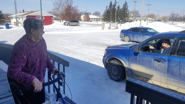 Une dame discute depuis le perron d'une maison.