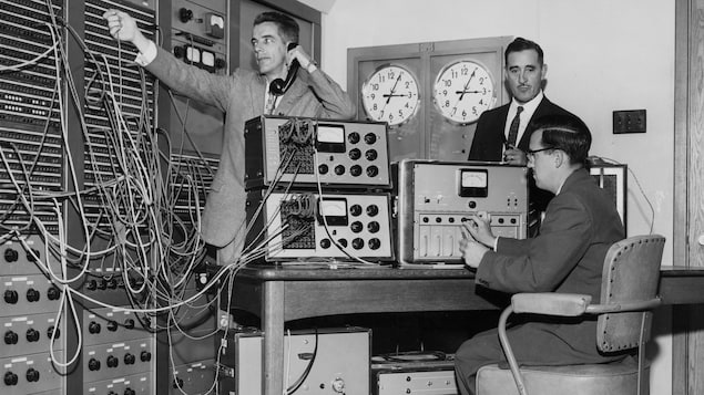 Lors de la visite royale, trois techniciens s'affairent dans une régie centrale de radio.