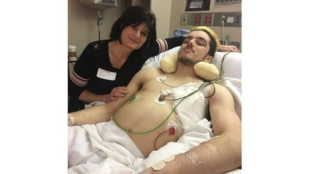 Une femme est assise à côté d'un homme couché sur un lit d'hôpital.