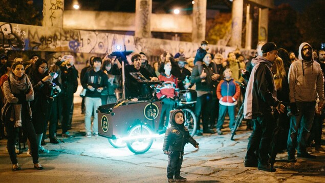 Une foule regarde des projections provenant d'un tricycle. Une foule regarde des projections provenant d'un tricycle.