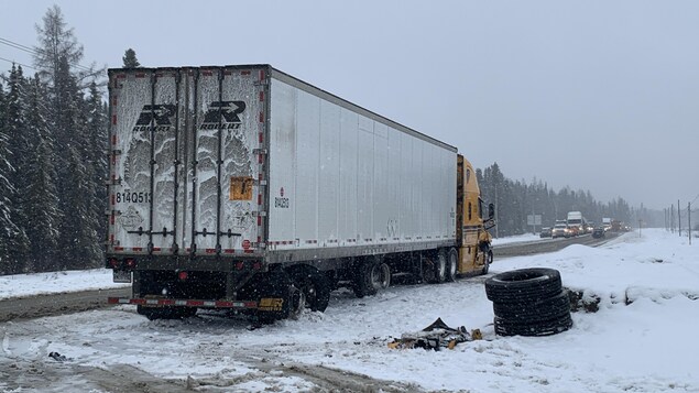 Un camion poids lourd sorti de route, quelques pneus empilés et des morceaux de ferraille tout juste à côté.