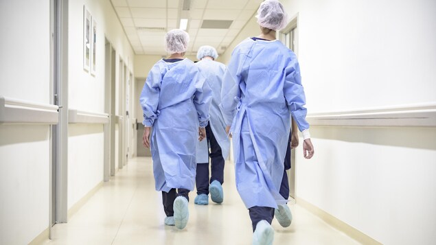 Des infirmières marchent de dos dans le corridor d'un hôpital.
