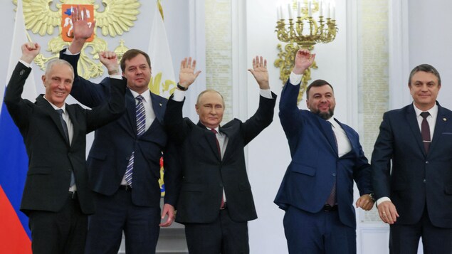 Vladimir Poutine au centre avec les quatre autres dirigeants célébrant les bras dans les airs.