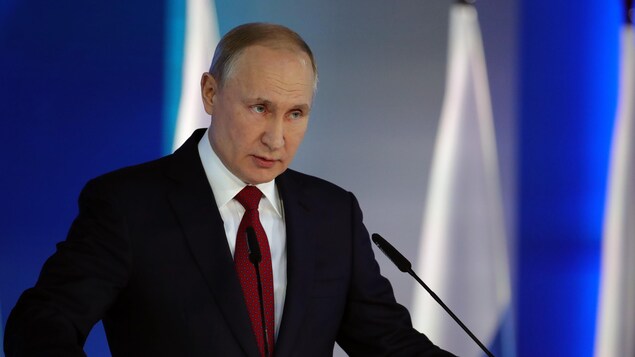 Vladimir Poutine s'adresse à une foule derrière un lutrin.