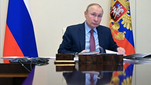 Vladimir Poutine assis à une table.