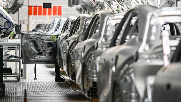 Un ouvrier inspecte une voiture électrique dans une usine.