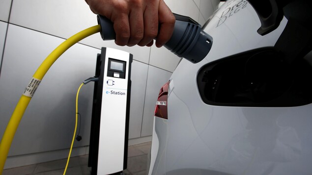 Un employé de Volkswagen pose avec une borne de recharge pour une voiture une e-Golf de la ligne de production allemande Transparent Factory. Un employé de Volkswagen pose avec une borne de recharge pour une voiture une e-Golf de la ligne de production allemande Transparent Factory.