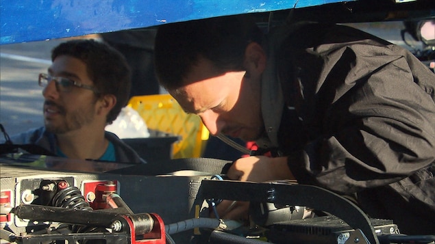 Un étudiant fait des vérifications techniques sous la coque de la voiture solaire. Un étudiant fait des vérifications techniques sous la coque de la voiture solaire.