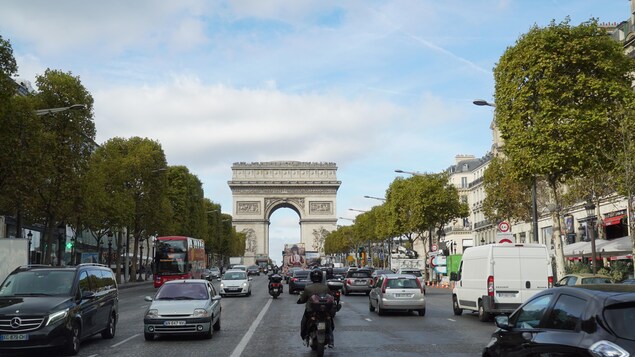 On voit des voitures et des motos circuler sur l'avenue des Champs-Élysées, à Paris. On voit des voitures et des motos circuler sur l'avenue des Champs-Élysées, à Paris.