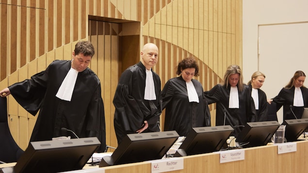 Des juges s’assoient dans une salle d'audience.