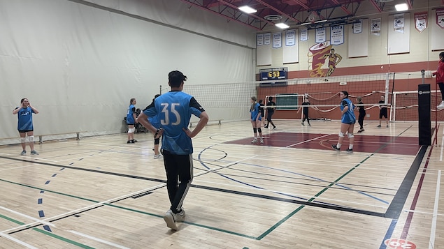 Des jeunes qui jouent au volleyball dans un gymnase.