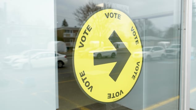 Une affiche indication l'endroit pour aller voter est installée dans une fenêtre.