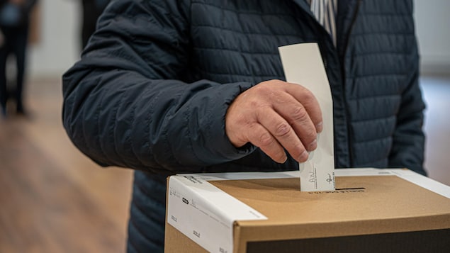 Una persona coloca un voto en una caja de cartón.