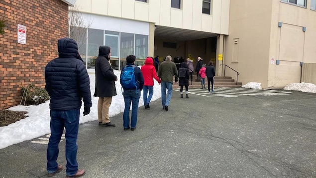 Des électeurs en rang à l'extérieur devant un bureau de vote par anticipation.