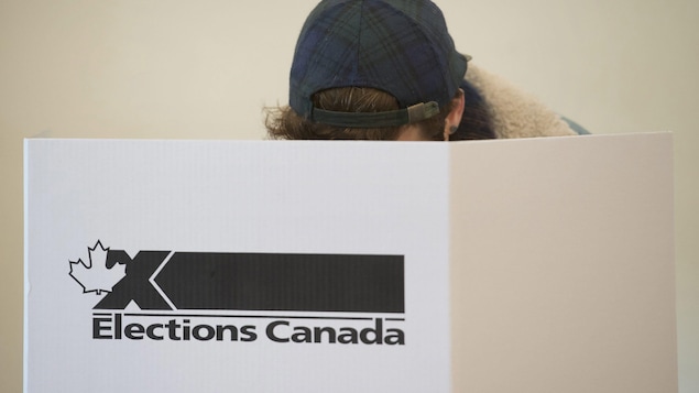 Un jeune homme passe au vote dans une urne d'Élections Canada.