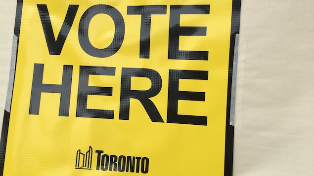 Photo d'une affiche jaune sur laquelle est écrit : « Vote here ».