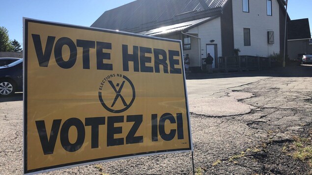 Une pancarte sur le sol sur laquelle il est écrit « VOTE HERE - VOTEZ ICI »