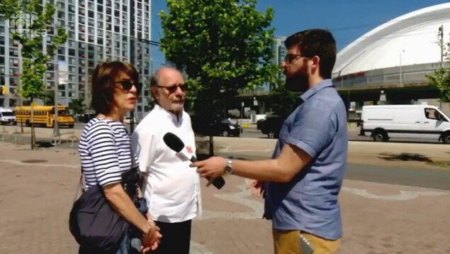 Le journaliste avec son microphone et deux promeneurs sur le sentier