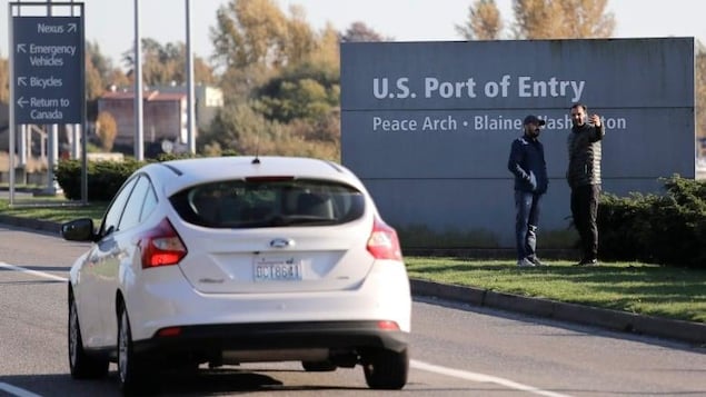 Un véchicule blanc s'approche d'un service frontalier vers les États-Unis. 