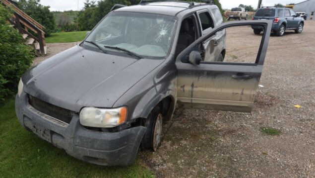 Un VUS gris accidenté avec un pneu crevé et le pare-brise craqué.