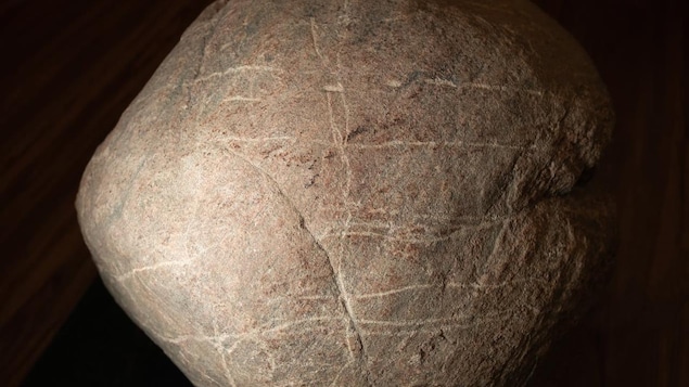 Une pierre de forme ronde sur laquelle sont tracées des stries.