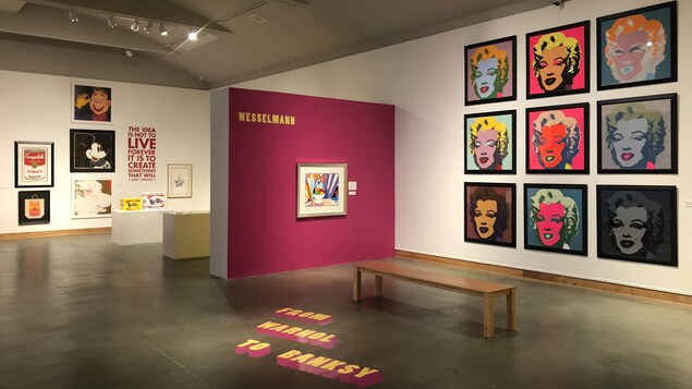 Des toiles de divers artistes tels Andy Warhol et Tom Wesselmann exposées dans une galerie. Sur le sol est écrit «From Warhol to Banksy».