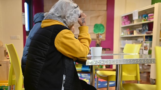 Une personne âgée assise à une table.
