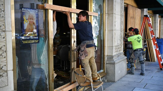 Des ouvriers réparent la devanture d’un restaurant.