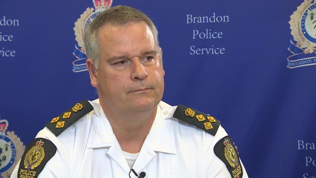 Un policier devant un fond bleu de la police de Brandon.