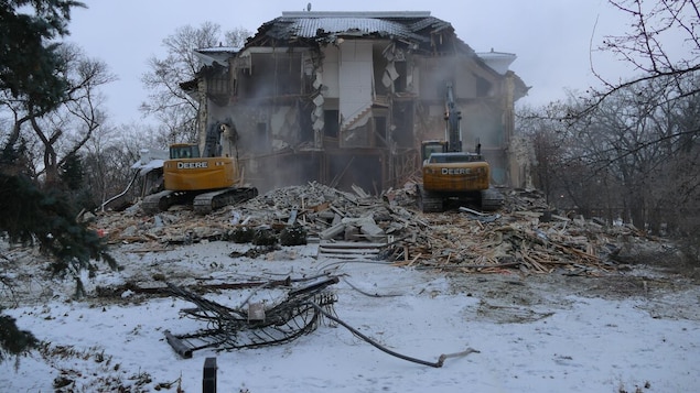 De la poussière remplit l'air et les murs s'écroulent sous le poids des deux tracteurs.