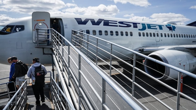La rampe d'un avion Westjet avec des voyageurs débarquant sur le tarmac.