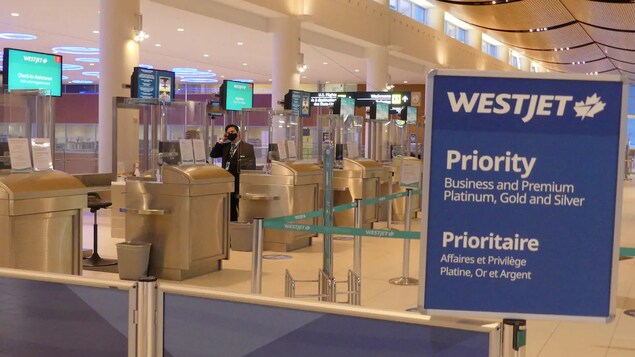 Une pancarte de WestJet avec des kiosques d’information et des écrans au-dessus. 