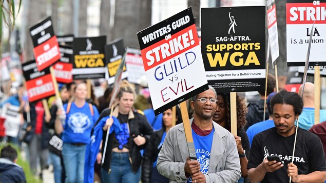Des personnes tiennent des pancartes lors d'une marche en soutien au mouvement de grève de la WGA.