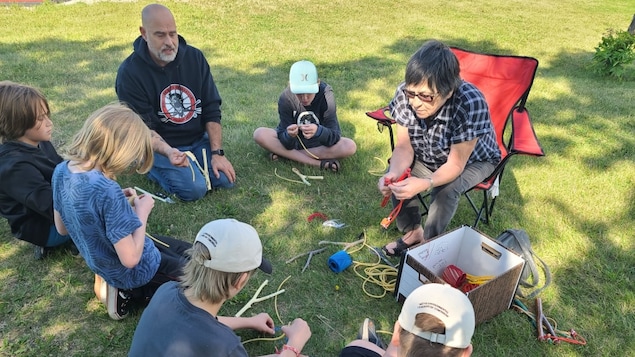 Will Goodon, à gauche, et Leah LaPlante, de la Fédération métisse du Manitoba, aident les jeunes à fabriquer des lance-pierres dans le cadre du programme MELT tenu à Brandon du 8 au 12 août 2022. 