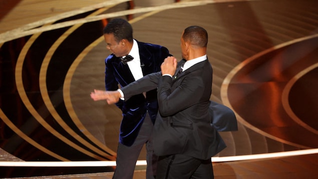 Un homme en frappe un autre avec sa main sur la scène des Oscars. 