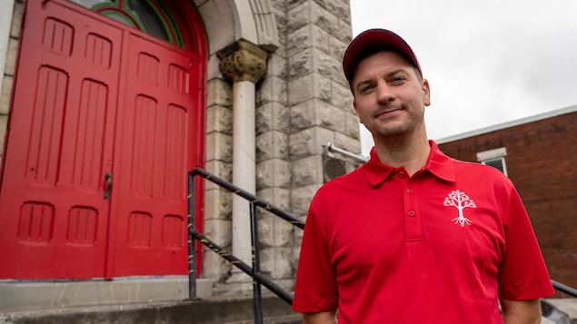 William Komer pose devant l'église Ste-Brigid.