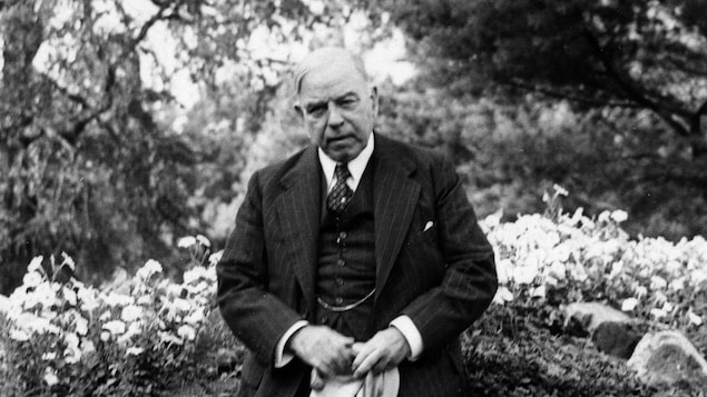 William Lyon Mackenzie King avec son chien dans un jardin.