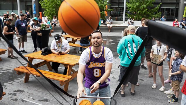 Une personne portant un chandail des Lakers lance des ballons de basketball.