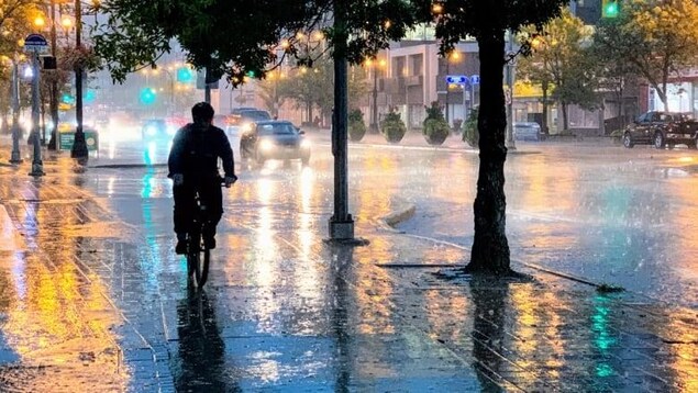 Un cycliste roule sous la pluie à Winnipeg.