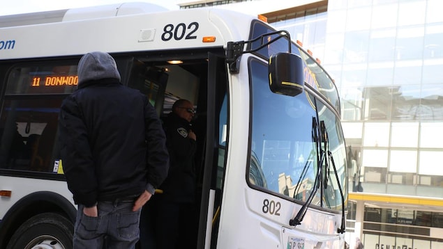 Un homme attend de monter dans un autobus municipal.