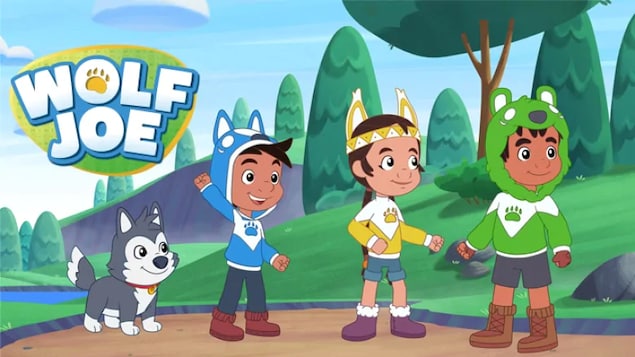Une image du personnage animé Wolf Joe accompagné de ses deux amis et d’un chien. Ils sont dans la forêt.