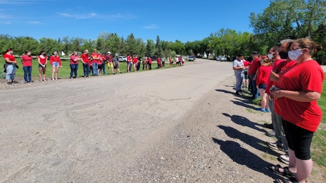 Des gens portent un chandail rouge sur le bord d'une route.