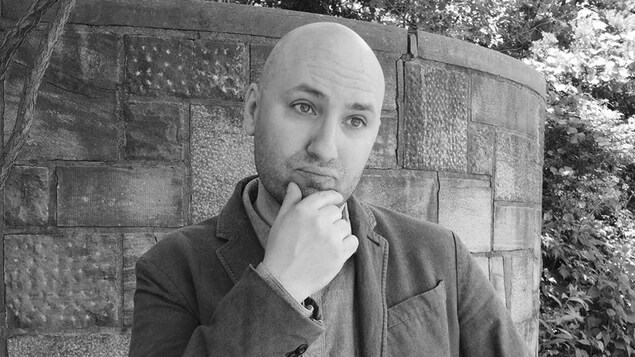L'homme, chauve, se tient le menton. La photo est en noir et blanc. L'homme, chauve, se tient le menton. La photo est en noir et blanc.